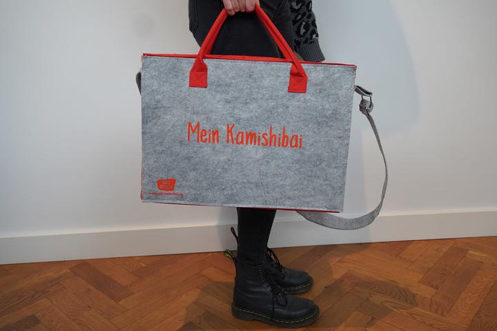 Produktbild Umhängetasche /"Mein Kamishibai/". Modell 2019. Aus grauem Filz, verstärktem Boden, roten Seitenteil